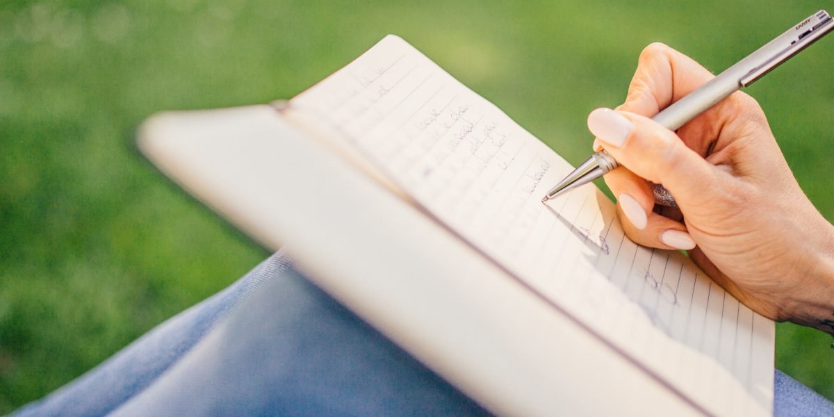 A person writing in a journal, embodying the practice of self-reflection and mindfulness for personal growth.