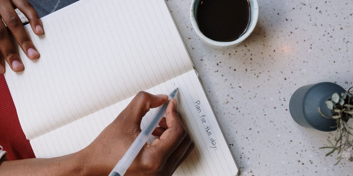 A person writing in a journal at a coffee shop, practicing self-reflection and gratitude.