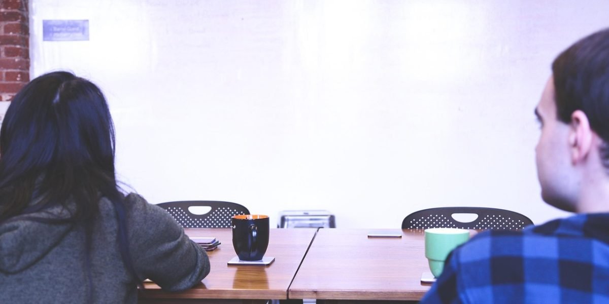 Two individuals collaborating and discussing ideas at a whiteboard, representing therapeutic and collaborative strategies.
